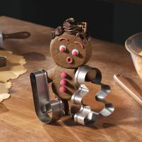 Gingerbread character holds up two cookie cutters